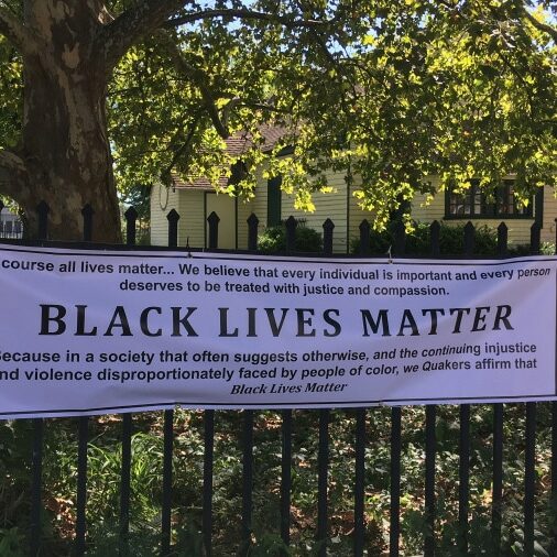 a Black Lives Manner banner hanging on the fence in front of a meetinghouse